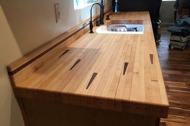 Inspiration for a mid-sized eclectic u-shaped medium tone wood floor eat-in kitchen remodel in Santa Barbara with an undermount sink, raised-panel cabinets, light wood cabinets, wood countertops, black appliances and no island