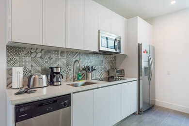Kitchen - modern single-wall kitchen idea in Chicago with flat-panel cabinets, white cabinets, stainless steel appliances and white countertops