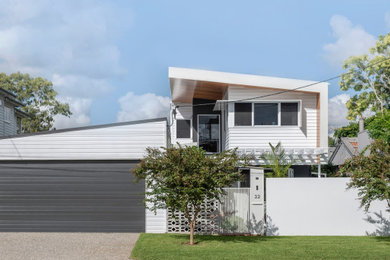 This is an example of a large modern three-storey multi-coloured house exterior in Brisbane with mixed siding, a metal roof and a white roof.