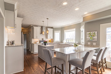 Eat-in kitchen - u-shaped brown floor eat-in kitchen idea in Cleveland with a drop-in sink, shaker cabinets, white cabinets, granite countertops, granite backsplash, stainless steel appliances and an island