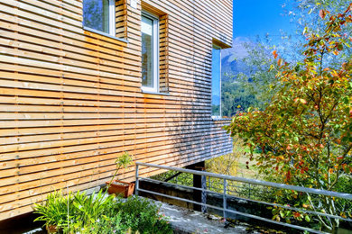 Foto della villa piccola contemporanea a due piani con rivestimento in legno, tetto piano e copertura verde