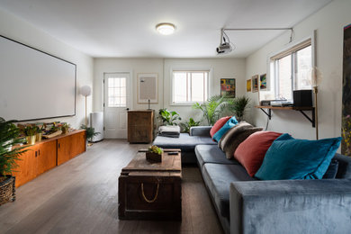 Example of a trendy medium tone wood floor and brown floor living room design in Toronto with white walls and a wall-mounted tv