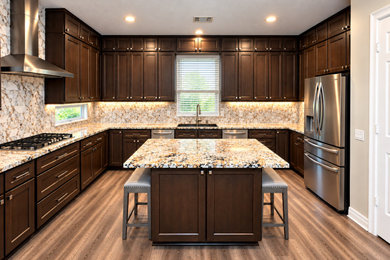 Inspiration for a large u-shaped kitchen remodel in Houston with an undermount sink, shaker cabinets, dark wood cabinets, granite countertops, beige backsplash, porcelain backsplash, stainless steel appliances, an island and beige countertops