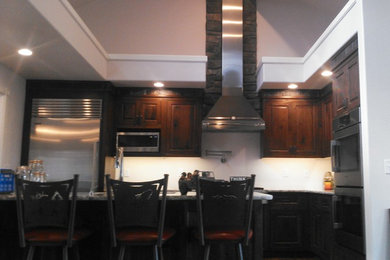 Example of a mid-sized mountain style l-shaped dark wood floor open concept kitchen design in Other with an undermount sink, beaded inset cabinets, dark wood cabinets, granite countertops, stainless steel appliances and an island