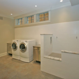 シカゴの大きいトラディショナルスタイルのおしゃれな家事室 (フラットパネル扉のキャビネット、グレーのキャビネット、ステンレスカウンター、グレーの壁、セラミックタイルの床、左右配置の洗濯機・乾燥機) の写真