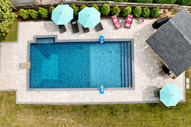Design ideas for a beach style rectangular pool in New York with a pool house and concrete pavers.