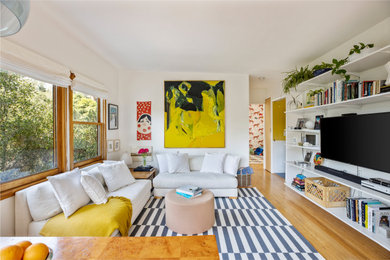 Trendy medium tone wood floor and brown floor family room photo in San Francisco with white walls and a wall-mounted tv