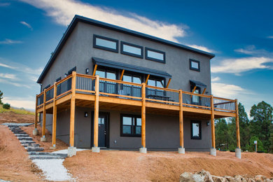 Large minimalist blue two-story stucco house exterior photo in Other with a shed roof, a shingle roof and a black roof