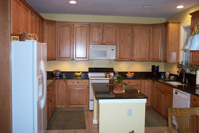 Example of a mid-sized classic u-shaped eat-in kitchen design in Baltimore with an undermount sink, medium tone wood cabinets, granite countertops, black backsplash, white appliances and an island