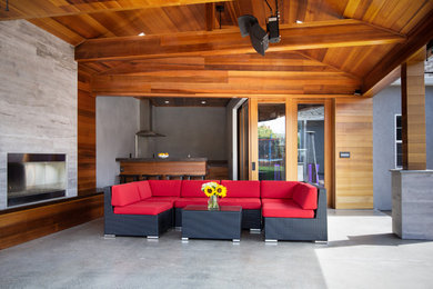 Inspiration for a mid-sized industrial concrete back porch remodel in San Francisco with a fireplace and a roof extension