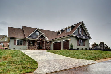 Example of a large transitional green one-story brick exterior home design in Other with a shingle roof