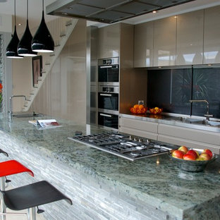 Large contemporary kitchen pantry photos - Large trendy galley concrete floor kitchen pantry photo in Adelaide with a double-bowl sink, flat-panel cabinets, gray cabinets, granite countertops, black backsplash, glass sheet backsplash, stainless steel appliances and an island