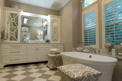 Photo of a large traditional master bathroom in Other with raised-panel cabinets, white cabinets, a freestanding tub, an alcove shower, a one-piece toilet, beige walls, an undermount sink, a hinged shower door, marble benchtops, multi-coloured floor and white benchtops.