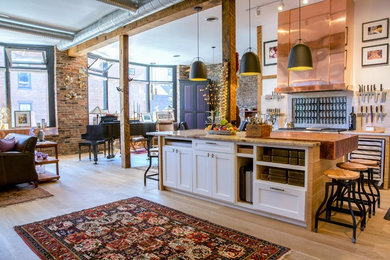 Inspiration for a small industrial l-shaped open plan kitchen in Boston with shaker cabinets, white cabinets, marble benchtops, beige splashback, stone slab splashback, stainless steel appliances, a peninsula, an undermount sink, light hardwood floors and brown floor.
