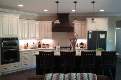 Example of a large classic l-shaped eat-in kitchen design in Other with an undermount sink, raised-panel cabinets, white cabinets, granite countertops, black appliances, an island and multicolored countertops