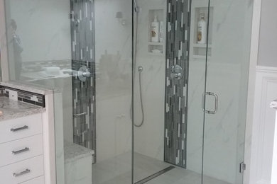 Example of a large classic master gray tile and mosaic tile porcelain tile, gray floor, double-sink and wainscoting bathroom design in Seattle with recessed-panel cabinets, white cabinets, a one-piece toilet, gray walls, an undermount sink, quartz countertops, a hinged shower door, gray countertops and a built-in vanity
