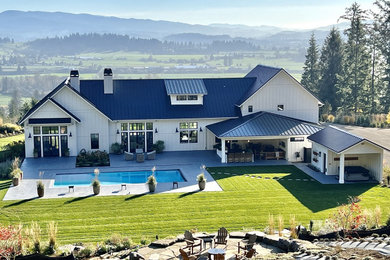Inspiration for a large cottage white two-story wood and board and batten exterior home remodel in Portland with a metal roof and a black roof