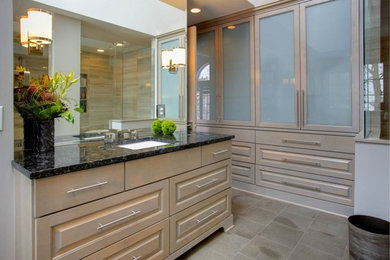 Design ideas for a mid-sized contemporary master bathroom in Minneapolis with raised-panel cabinets, a corner shower, porcelain floors, an undermount sink, granite benchtops, beige cabinets, grey walls, brown floor and a hinged shower door.