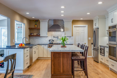 Inspiration for a large transitional u-shaped medium tone wood floor open concept kitchen remodel in Baltimore with a single-bowl sink, shaker cabinets, white cabinets, marble countertops, white backsplash, porcelain backsplash, stainless steel appliances, an island and white countertops