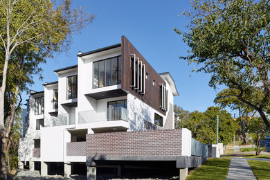 This is an example of an expansive modern three-storey concrete white exterior in Brisbane with a flat roof.