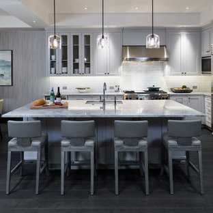 На фото: угловые кухни в стиле современная классика с обеденным столом, врезной раковиной, фасадами в стиле шейкер, серыми фасадами, белым фартуком, фартуком из плитки кабанчик, техникой из нержавеющей стали и темным паркетным полом