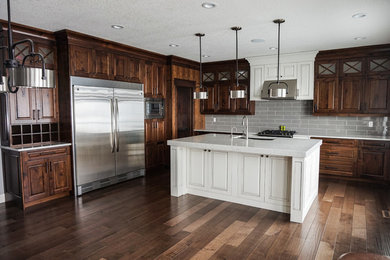 Inspiration for a large timeless l-shaped medium tone wood floor and brown floor kitchen pantry remodel in Calgary with an undermount sink, raised-panel cabinets, brown cabinets, quartz countertops, gray backsplash, ceramic backsplash, stainless steel appliances, an island and white countertops