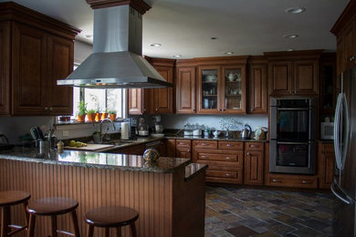 Large elegant u-shaped slate floor eat-in kitchen photo in DC Metro with raised-panel cabinets, brown cabinets, granite countertops and stainless steel appliances