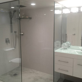 Foto di una stanza da bagno minimalista con ante lisce, ante bianche, WC monopezzo, piastrelle beige, piastrelle in gres porcellanato, pareti bianche, pavimento in cemento, lavabo integrato, top in vetro riciclato e doccia aperta