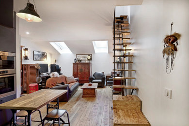 Cette photo montre une salle de séjour mansardée ou avec mezzanine industrielle de taille moyenne avec un sol en bois brun, un mur blanc et un téléviseur fixé au mur.