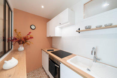 Réalisation d'une petite cuisine linéaire et encastrable tradition fermée avec un évier encastré, un placard à porte plane, des portes de placard blanches, un plan de travail en bois, une crédence blanche, une crédence en céramique, carreaux de ciment au sol, aucun îlot, un sol beige et un plan de travail marron.