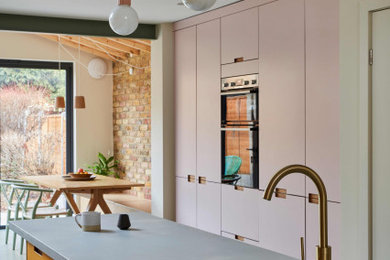 Photo of a contemporary kitchen in London with a submerged sink, flat-panel cabinets, pink cabinets, concrete worktops, white splashback, ceramic splashback, lino flooring, an island, green floors, grey worktops, a timber clad ceiling and feature lighting.