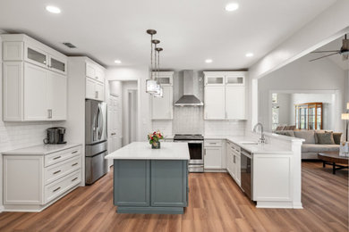 Example of a transitional vinyl floor and brown floor eat-in kitchen design in Dallas with an undermount sink, shaker cabinets, white cabinets, quartz countertops, white backsplash, subway tile backsplash, stainless steel appliances, an island and white countertops