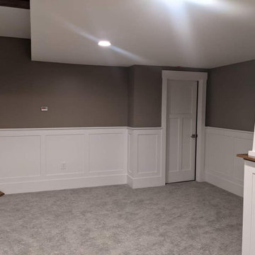 Basement with a banquette, beams, wainscot and bookcases