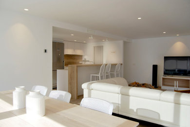 Пример оригинального дизайна: большая открытая гостиная комната в белых тонах с отделкой деревом в средиземноморском стиле с белыми стенами, полом из керамической плитки и телевизором на стене