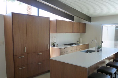 1950s linoleum floor and multicolored floor kitchen photo in Los Angeles with an undermount sink, flat-panel cabinets, light wood cabinets, quartz countertops, white backsplash, paneled appliances, an island and white countertops