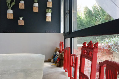 Cette photo montre une grande cuisine linéaire éclectique avec des portes de placard noires, un plan de travail en quartz modifié, une crédence noire, sol en béton ciré, îlot, un sol gris et plan de travail noir.