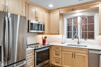 Kitchen photo in St Louis with a double-bowl sink, light wood cabinets, white backsplash and white countertops