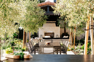 Mid-sized tuscan backyard stone patio photo in Orange County with a fireplace and a gazebo