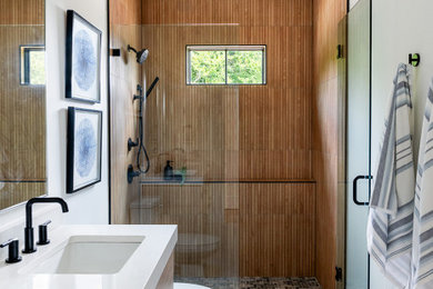 This is an example of a modern ensuite bathroom in Richmond with light wood cabinets and double sinks.