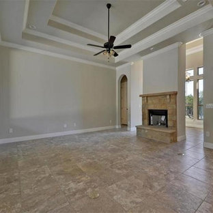 Modelo de salón para visitas abierto, mediterráneo, grande, con paredes beige, suelo de baldosas de cerámica, chimenea tradicional, marco de chimenea de piedra y televisor colgado en la pared