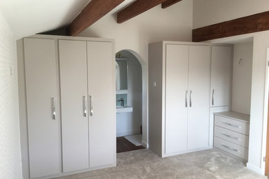 Photo of a medium sized contemporary gender neutral standard wardrobe with flat-panel cabinets, grey cabinets and carpet.