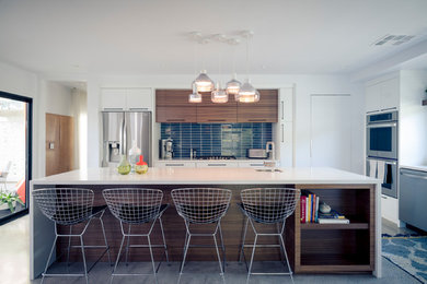 This is an example of a mid-sized midcentury single-wall eat-in kitchen in Las Vegas with an undermount sink, flat-panel cabinets, white cabinets, quartz benchtops, blue splashback, ceramic splashback, stainless steel appliances, concrete floors, with island and grey floor.