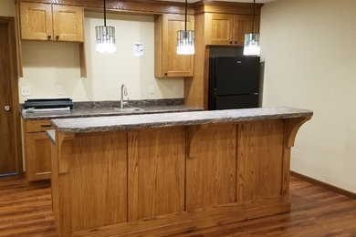 Open concept kitchen - small traditional single-wall dark wood floor and brown floor open concept kitchen idea in Other with a drop-in sink, shaker cabinets, medium tone wood cabinets, granite countertops, black appliances and an island
