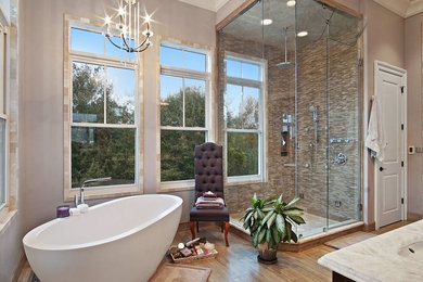 Mid-sized transitional master bathroom in New Orleans with a freestanding tub, a corner shower, beige tile, matchstick tile, beige walls, medium hardwood floors, an undermount sink, marble benchtops, brown floor, a hinged shower door and beige benchtops.