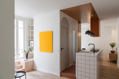 Inspiration for a mid-sized scandinavian single-wall open plan kitchen in Paris with an integrated sink, beaded inset cabinets, light wood cabinets, tile benchtops, panelled appliances, terra-cotta floors, with island, brown floor and white benchtop.