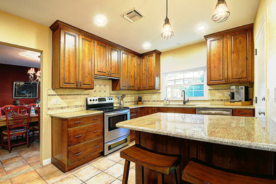 Kitchen - rustic kitchen idea in Orlando with raised-panel cabinets, distressed cabinets, granite countertops and stone tile backsplash