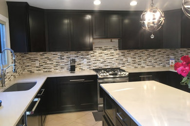 This is an example of a mid-sized contemporary u-shaped kitchen in Detroit with an undermount sink, shaker cabinets, dark wood cabinets, quartz benchtops, grey splashback, matchstick tile splashback, stainless steel appliances, ceramic floors, with island, beige floor and white benchtop.