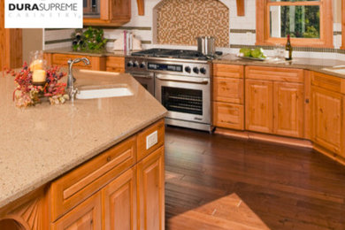 Example of a large classic l-shaped medium tone wood floor eat-in kitchen design in Other with an undermount sink, raised-panel cabinets, medium tone wood cabinets, quartz countertops, beige backsplash, stainless steel appliances and an island