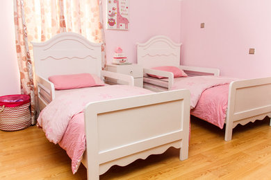 Inspiration for a small timeless girl laminate floor and brown floor kids' room remodel in Other with pink walls