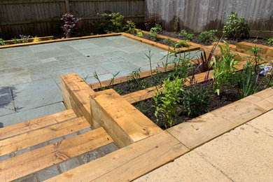 This is an example of a small contemporary back full sun garden for summer in Other with a raised bed and natural stone paving.